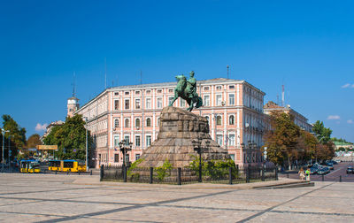 Statue in city against blue sky