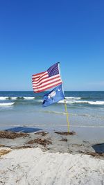 Flag on beach against clear blue sky