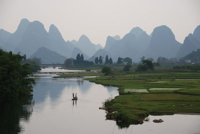 High angle view of people rafting in lake against mountains and sky