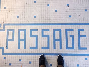 Low section of man standing by text on tiled floor