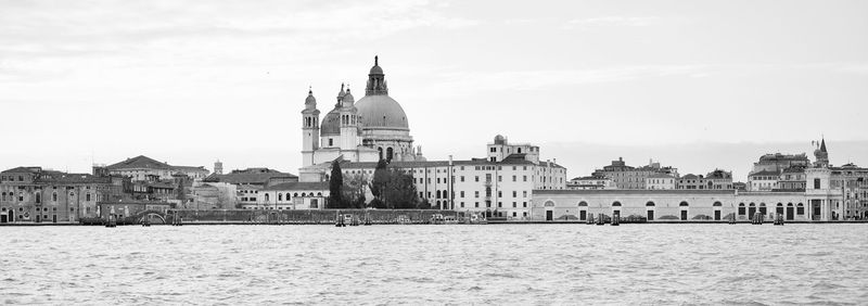 View of buildings by sea against sky in city