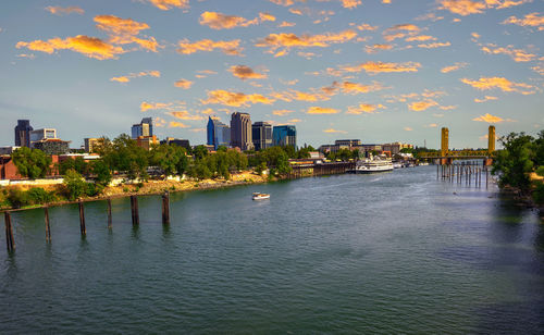 Buildings by river against sky