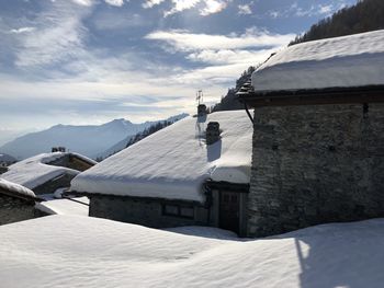 Snow covered houses by mountain against sky
