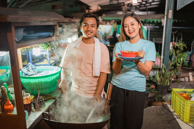 Portrait of smiling young woman holding food at market