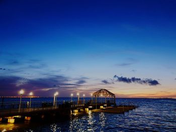 Pier over sea against sky at sunset