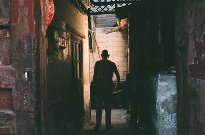 Rear view of man standing by wall in building