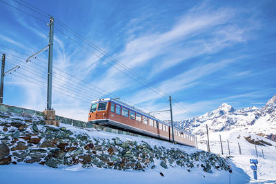 Famous red train running towards gornergrat station on mountain against sky