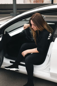 Young woman sitting on car