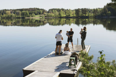 Group of friends with babies standing on deck at lake