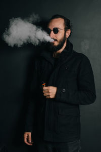 Man smoking while standing against wall