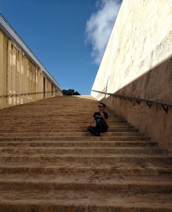 Low angle view of woman looking away sitting on staircase