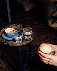 Cropped hands holding coffee by table at home