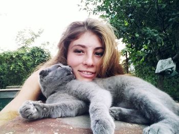 Portrait of smiling young woman sitting against plants