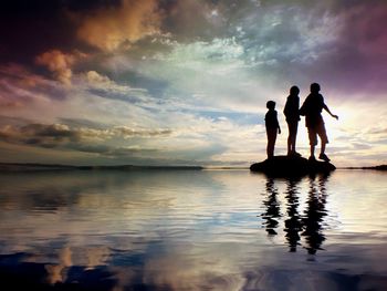 Silhouette of people in sea at sunset