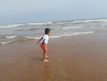 Full length of boy on beach against sky