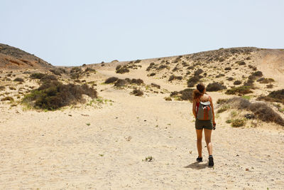 Rear view of woman walking at desert