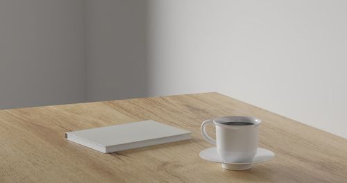 Close-up of coffee cup on table against wall at home