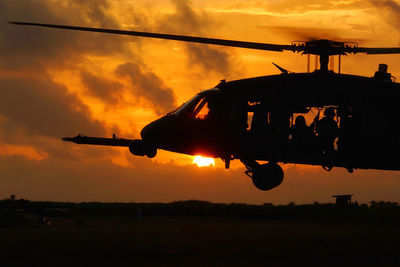 Military helicopter over field against sky during sunset