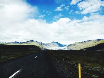 Road by mountains against sky