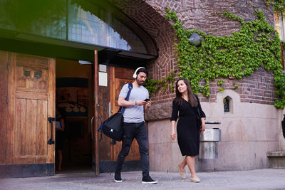 Full length of young woman standing against building