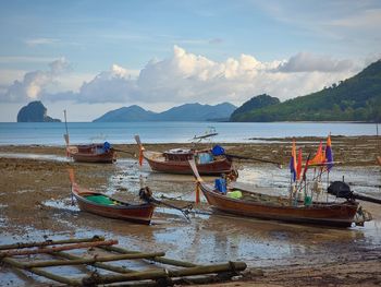 Scenic view of sea against sky with moored long tail boats