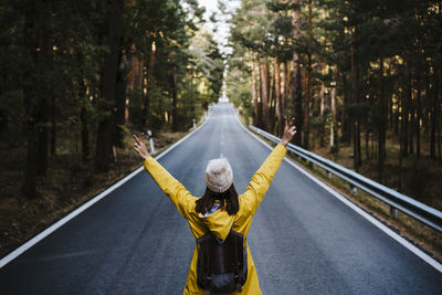 Woman with umbrella on road in forest