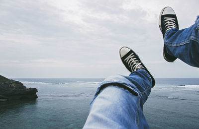 Low section of man at beach against sky