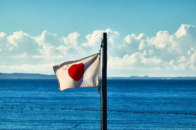 Japanese national red flag on sea against blue sky
