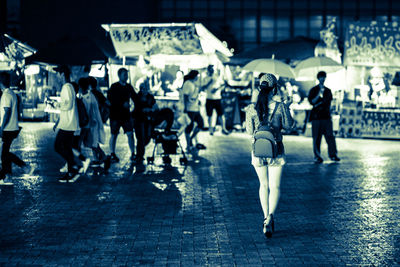 People walking on wet street at night