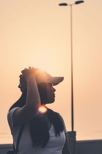 Woman looking away against sky during sunset