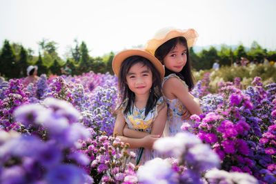 Portrait of happy girl with pink flowers against plants