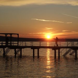 Pier over sea against sky during sunset