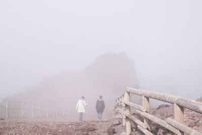 Rear view of people walking on mountain in foggy weather