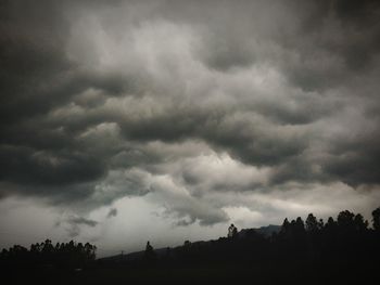 Silhouette of trees against cloudy sky