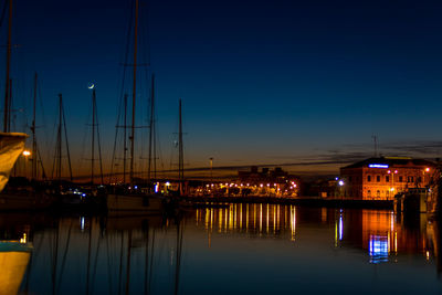 Sailboats moored in river against sky at night