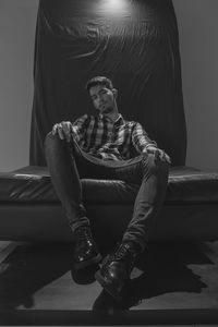 A portrait from low angle of a man with his leather shoes posing while sitting on the leather seat
