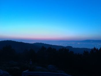 Scenic view of silhouette mountains against clear blue sky during sunset