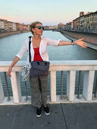 Woman standing on railing against water