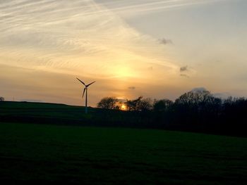 Windmill on field against sky during sunset