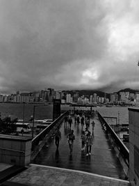 Bridge over river in city against cloudy sky