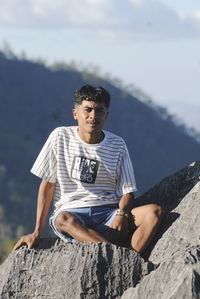 Young man sitting on rock