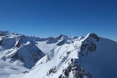 Scenic view of snowcapped mountains against clear blue sky