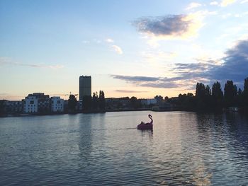 Sunset over calm river with buildings in background