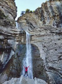 Full length of man surfing on rock against waterfall