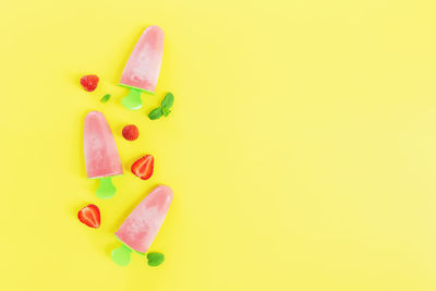 Close-up of fresh pink fruits over yellow background
