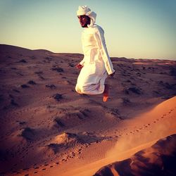 Full length of man levitating against clear sky at desert