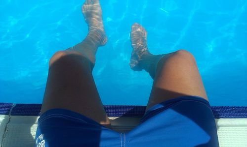 Low section of man relaxing at poolside