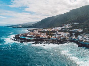 Aerial view of sea by mountains against sky