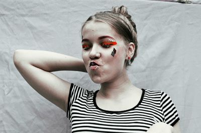 Close-up of young woman with make-up puckering lips by white fabric