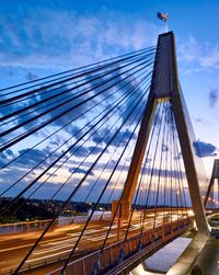 Low angle view of suspension bridge against cloudy sky